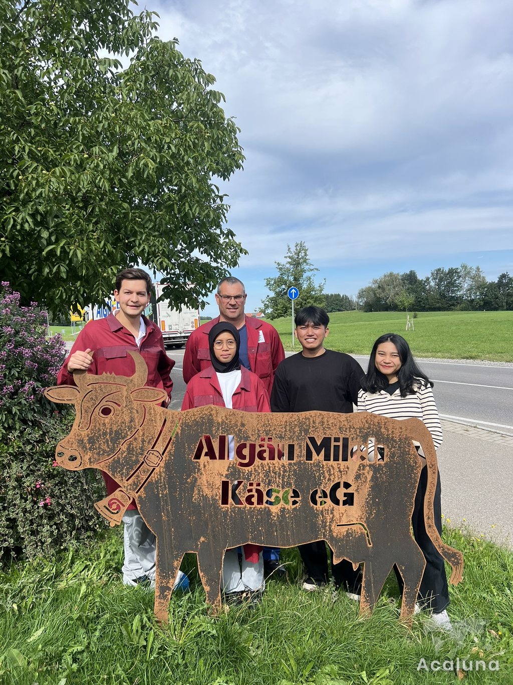 Internationale Auszubildende mit Kollegen vor einer Molkerei im Allgäu