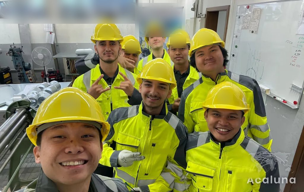Peserta Ausbildung teknisi isolasi dengan helm dan pakaian keselamatan di bengkel pelatihan